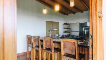 Una cocina con sillas de madera, una mesa de comedor y lámparas colgantes.
