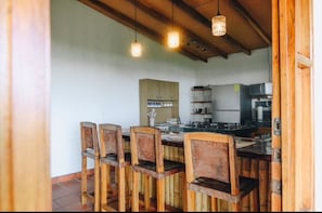 Uma cozinha com cadeiras de madeira, uma mesa de jantar e luminárias pendentes.