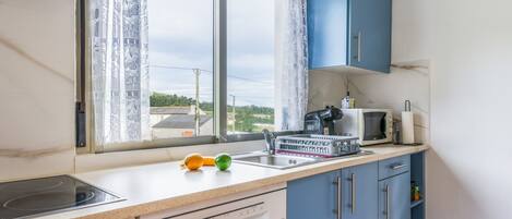 A kitchen with a window, a microwave, a coffee maker, and a dishwasher.