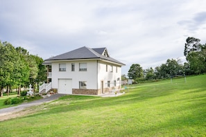 A two-story house with a white exterior, a stone foundation, and a grey roof.