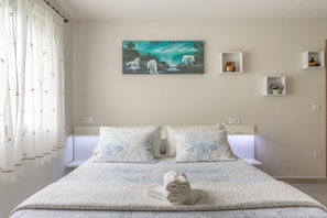 A hotel room with a bed, a painting, and a window with curtains.