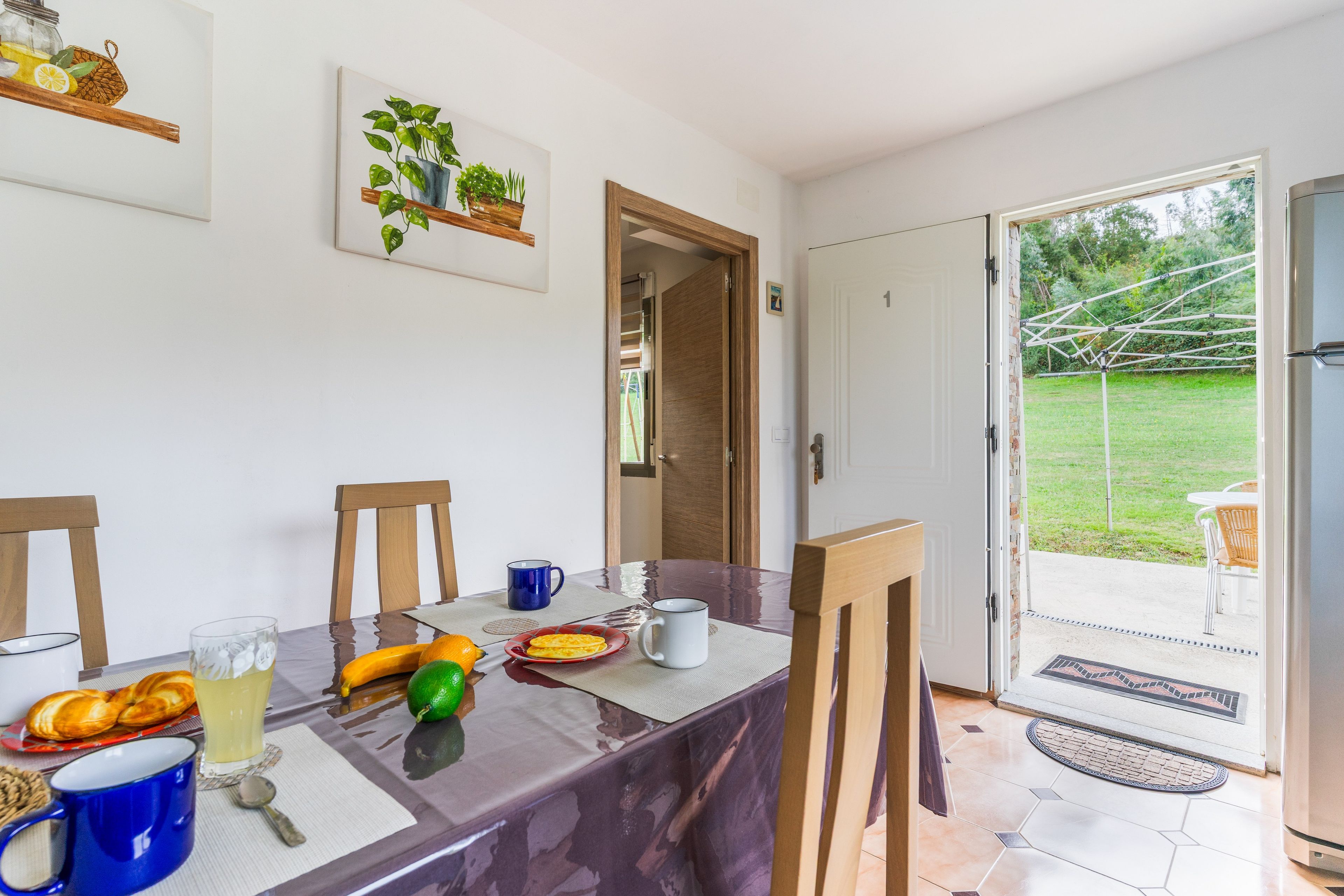 A dining area with a table set for breakfast, including bread, fruit, and beverages.