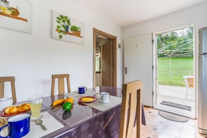 A dining area with a table set for breakfast, including bread, fruit, and beverages.