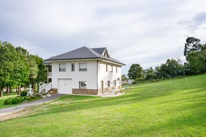 A two-story house with a white exterior, a stone foundation, and a grey roof.