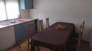 A compact kitchen with a dining table, chairs, and a sink.