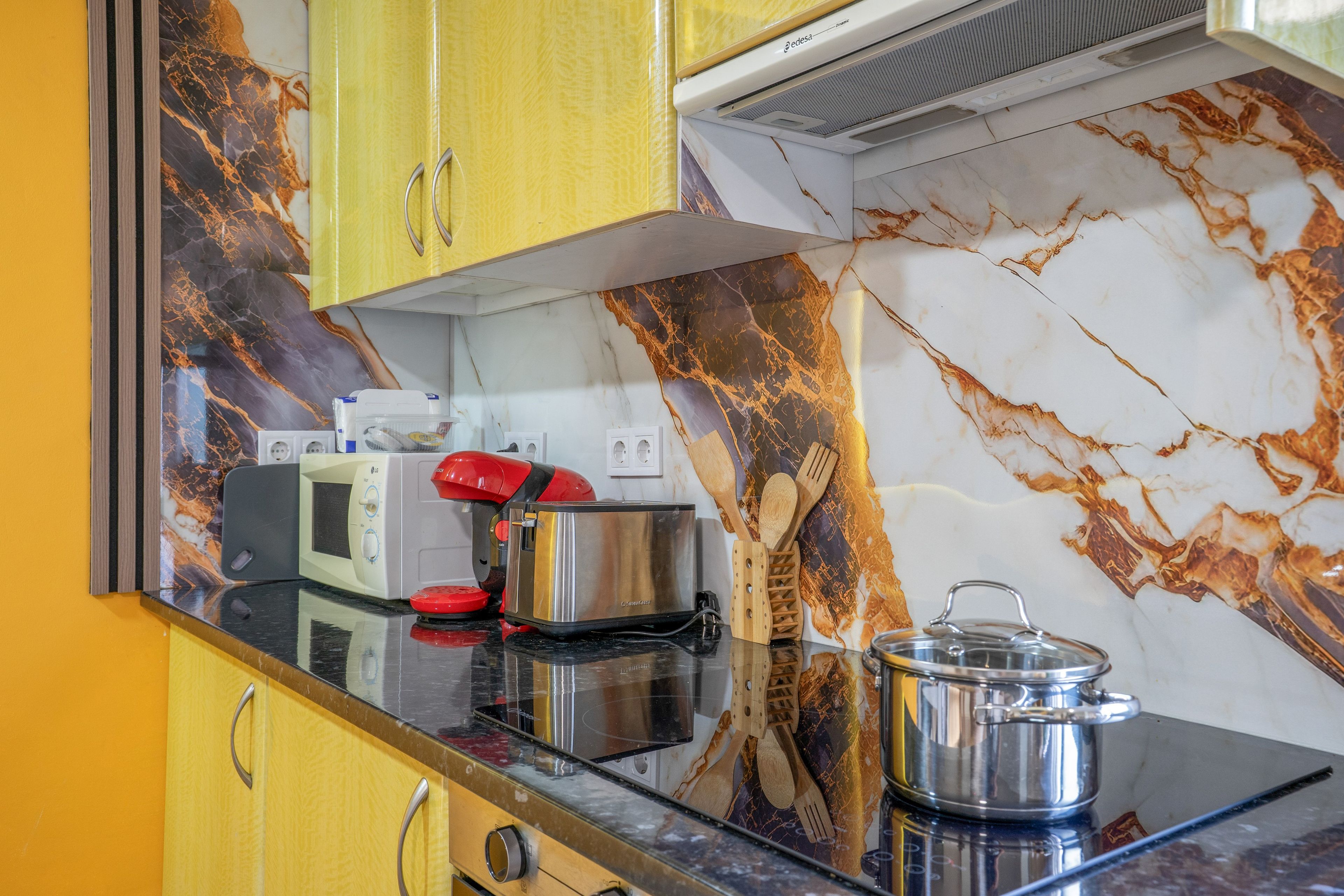 A kitchen with a microwave, toaster, and a pot on the counter.