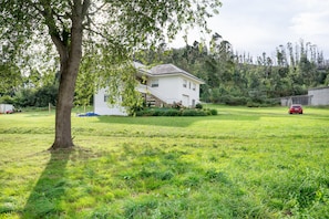 Ein weißes Haus mit Balkon, umgeben von einer grünen Wiese und Bäumen.