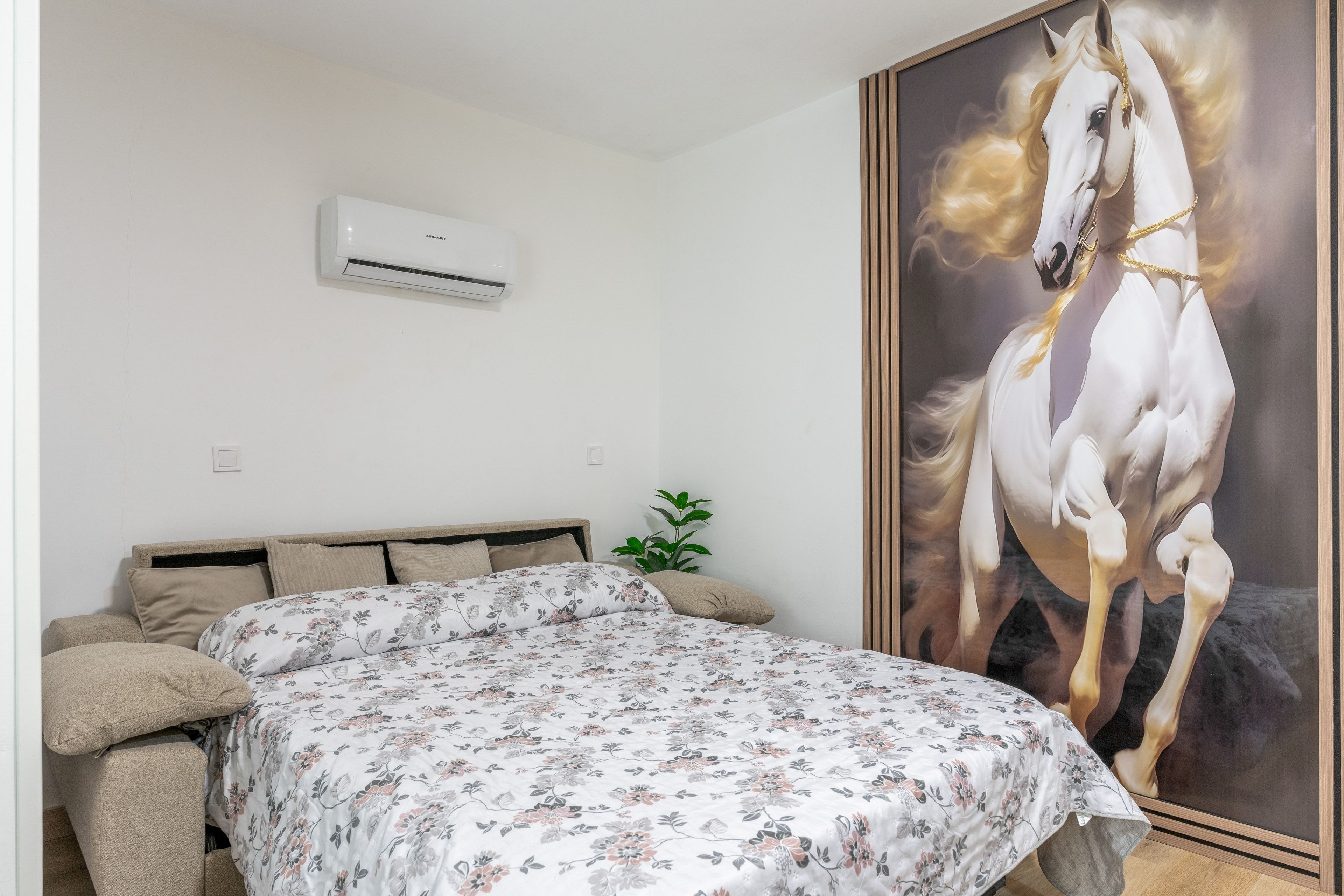 Ein Schlafzimmer mit einem Bett, einer Wandklimaanlage und einem großen Bild eines Pferdes.