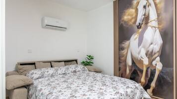 Ein Schlafzimmer mit einem Bett, einer Wandklimaanlage und einem großen Bild eines Pferdes.