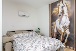 Ein Schlafzimmer mit einem Bett, einer Wandklimaanlage und einem großen Bild eines Pferdes.