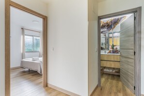 A hotel room with a bed, a window, and a bathroom with a mirror and sink.