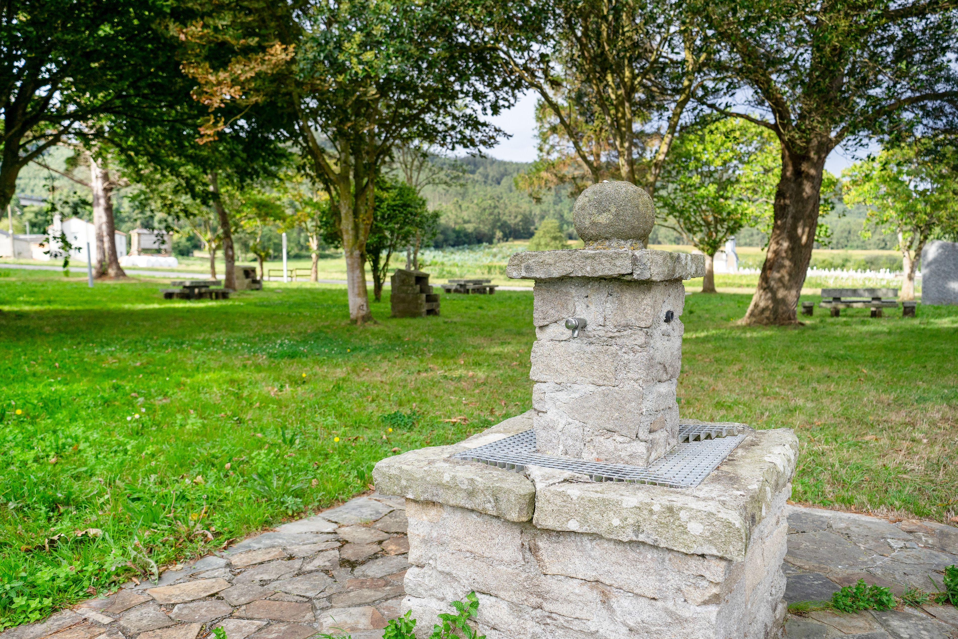 Un monument en pierre surmonté d’une sphère, entouré d’un sentier en pierre et d’une pelouse.