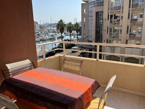 Ein Balkon mit Tisch und Stühlen mit Blick auf eine Marina, wo Boote und ein Hotel im Hintergrund zu sehen sind.