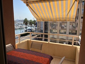Een balkon met uitzicht op een jachthaven, een tafel met een tafelkleed met patroon, en een stoel.
