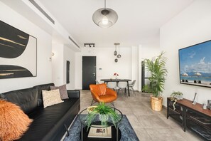 Een moderne woonkamer met een zwarte leren bank, een ronde salontafel, en een eethoek met een tafel en stoelen.