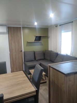 Ein modernes Wohnzimmer mit einem Holzespeisetisch, einem grauen Sofa und einer Einbauschränken mit einem Flachbildfernseher.