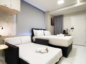 Habitación de hotel con dos camas, una mesita de noche, una lámpara, un cuadro y una puerta.