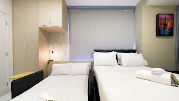 Quarto de hotel com duas camas, um guarda-roupa, uma mesa de cabeceira e um quadro na parede.