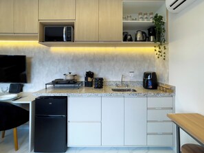 Una cocina moderna con microondas integrado, estufa, pileta y cafetera.