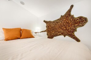 A bedroom with a bed, two orange pillows, and a large animal skin wall hanging. - [LaCasaDiUgo] In the heart of Lerici+A/C (Lerici)