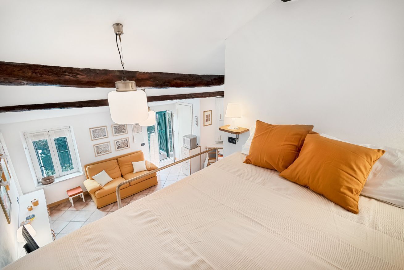A bedroom with a large bed, a sofa, a desk, and a window.