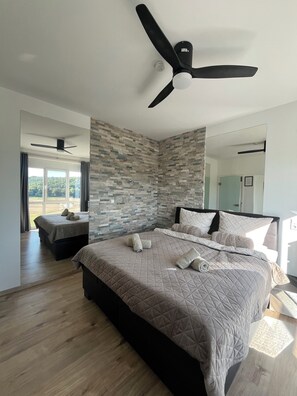 A modern bedroom with a large bed, a ceiling fan, and a stone-patterned wall.