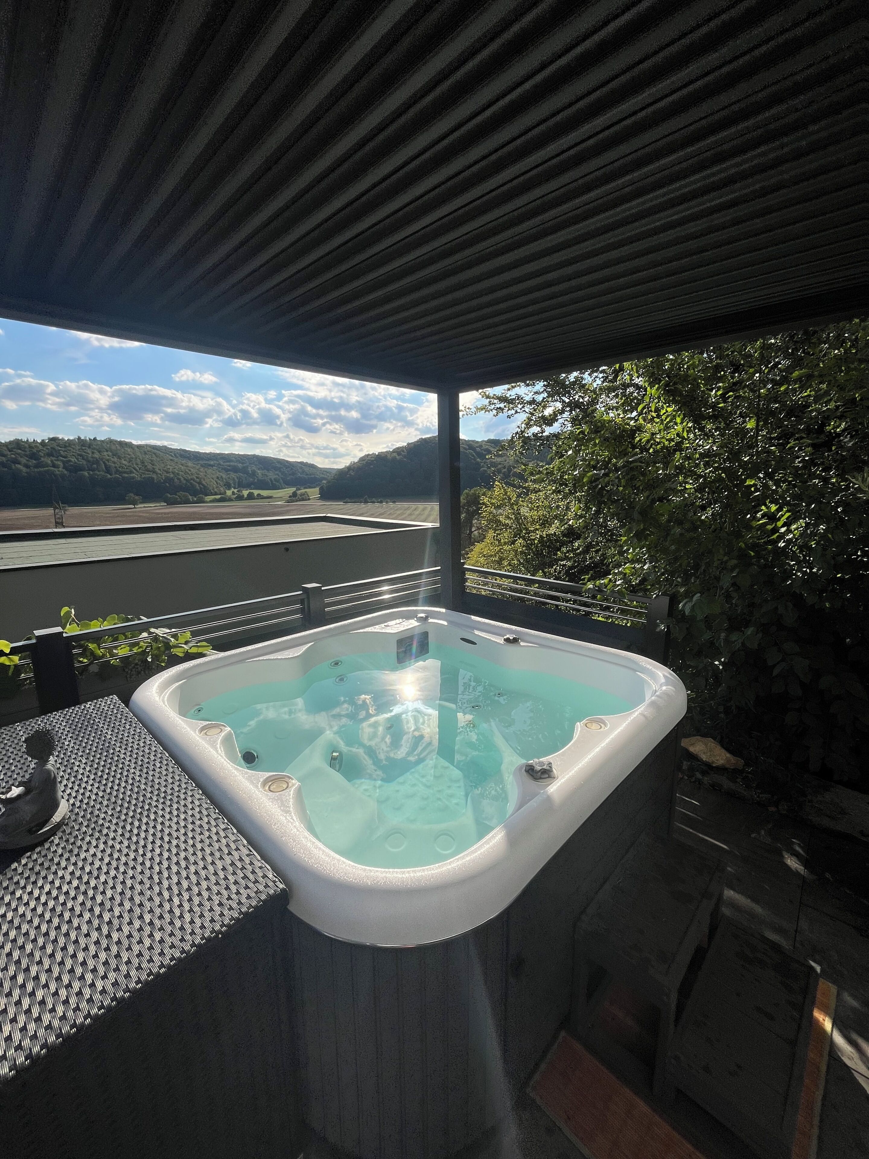 A hot tub with a view of a lake and hills.