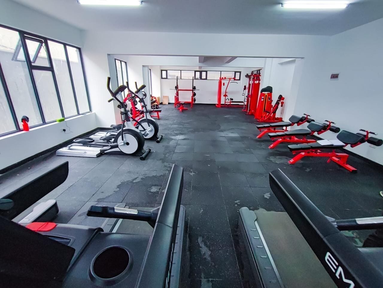Een sportschool met diverse fitnessapparaten, waaronder loopbanden en krachttoestellen.