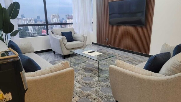 Ein modernes Wohnzimmer mit einer Sofagarnitur, einem Couchtisch und einem flachbildfernseher, der an einer Holzwand angebracht ist.