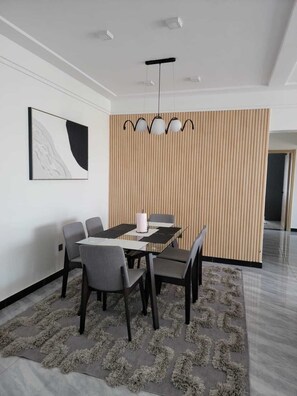 Una zona de menjador moderna amb una taula, cadires, una paret decorativa i un llum penjant.