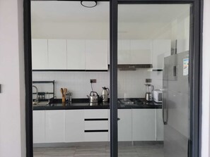Eine moderne Küche mit weißen Schränken, einer schwarzen Arbeitsplatte und Edelstahlgeräten, darunter ein Wasserkocher, ein Toaster und ein Mixer.