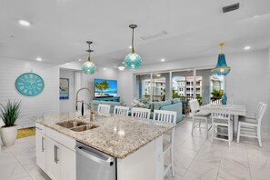 A modern kitchen with a central island, white cabinetry, and a built-in dishwasher. - Sister’s Paradise by AMI Locals (Bradenton)