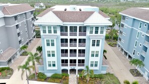 A multi-story building with a central entrance, surrounded by palm trees and a paved walkway. - Sister’s Paradise by AMI Locals (Bradenton)