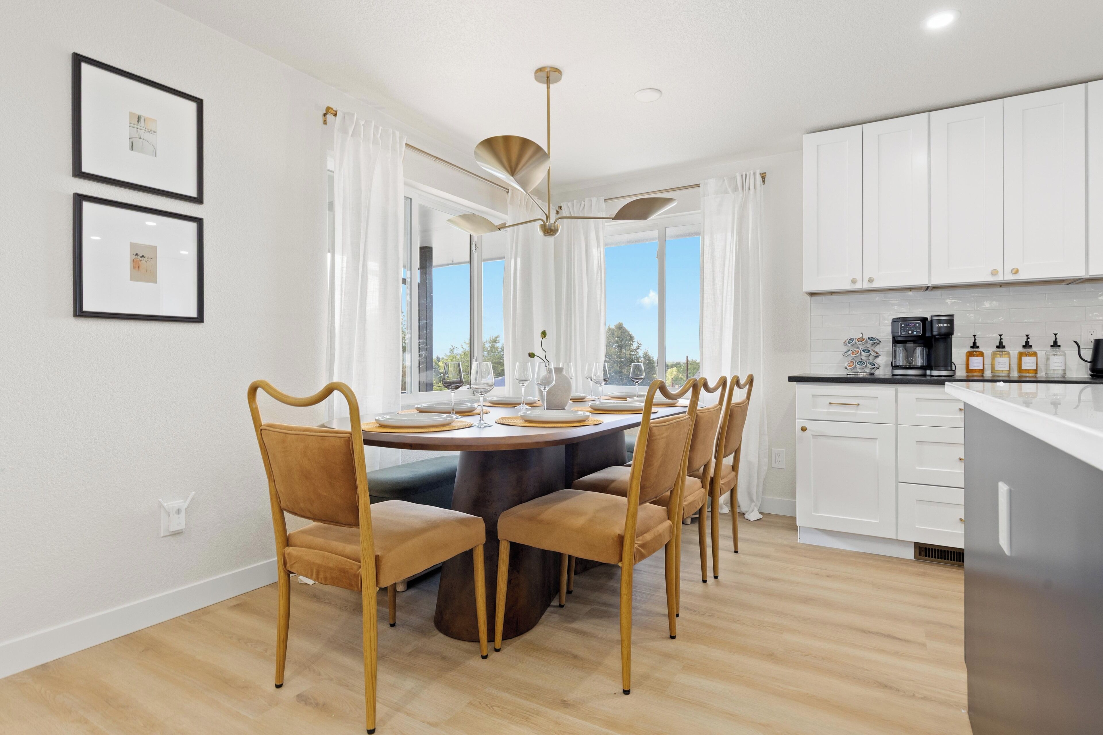 A modern kitchen with white cabinets, a dining area with a round table and chairs, and a ceiling fan.