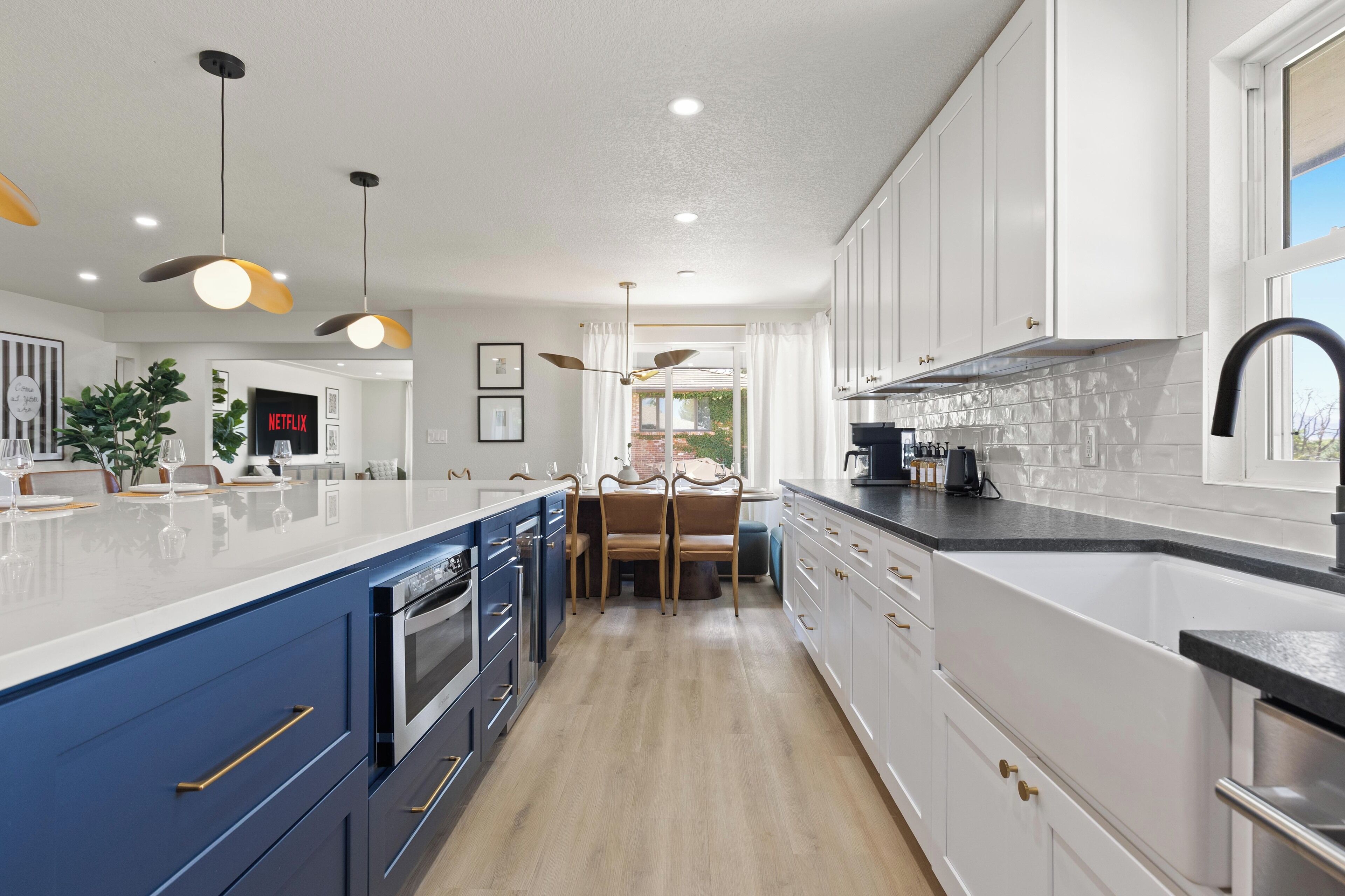 A modern kitchen with a central island, built-in appliances, and a dining area with a view.