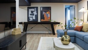 Ein modernes Wohnzimmer mit einem Ecksofa, einem Couchtisch und abstrakter Kunst an der Wand.
