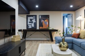 Ein modernes Wohnzimmer mit einem Ecksofa, einem Couchtisch und abstrakter Kunst an der Wand.