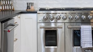 Eine moderne Küche mit weißen Schränken, einem Edelstahlkochfeld und einem eingebauten Backofen.