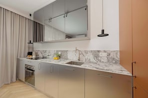 A compact kitchen with a built-in oven, a sink, and a marble backsplash. - Luxury Apartment in Chmielna Duo |Air Conditioning (Warszawa)