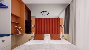 Een moderne slaapkamer met een bed, nachtkastje, wandklok en een raam met gordijnen.