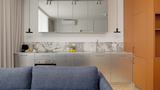 Een moderne keuken met een marmeren spatwand, grijze kastjes en een ingebouwde oven.