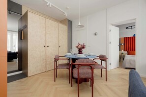 A modern dining area with a round table, four chairs, and a vase with flowers. - Luxury Apartment in Chmielna Duo |Air Conditioning (Warszawa)