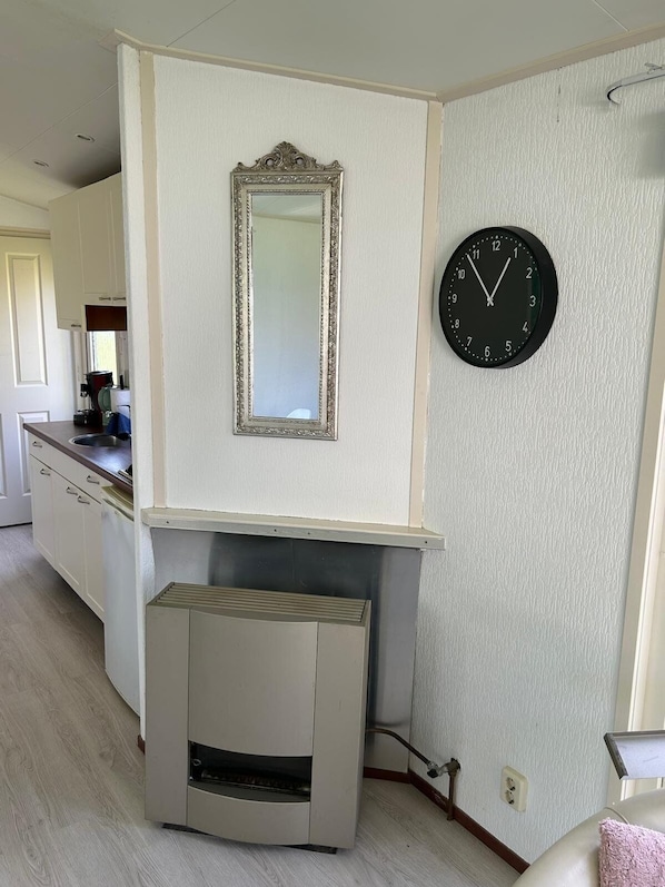 A kitchen with white cabinets, a mirror, a clock, and a built-in oven.