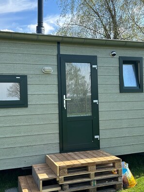 A mobile home with a dark green door, a small window, and a mailbox on the side.