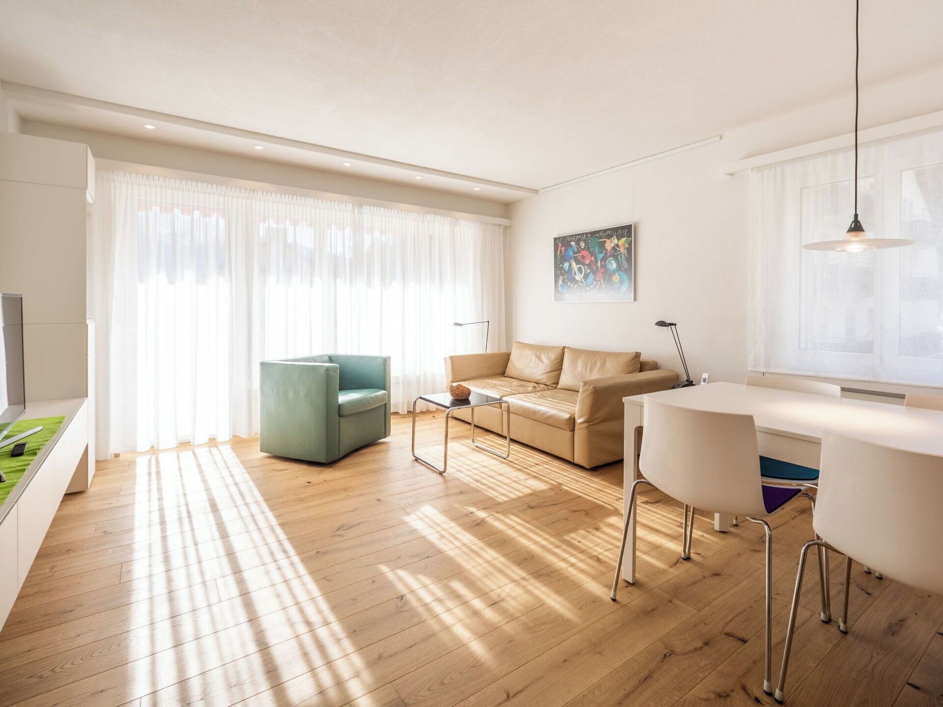 A modern living room with a sofa, a coffee table, and a dining area with a table and chairs.