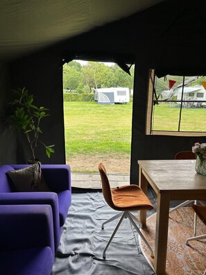 Una habitación con vista a un campo cubierto de césped, una caravana blanca y una mesa de comedor con un jarrón de flores.