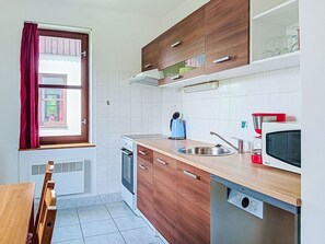 Eine kleine Küche mit Holzausstattung, einem Backofen, einer Mikrowelle und einem Spülbecken.
