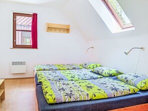 Ein Zimmer mit einem Bett, einem fenster mit Vorhängen, einem Wandheizgerät und einem Dachfenster.