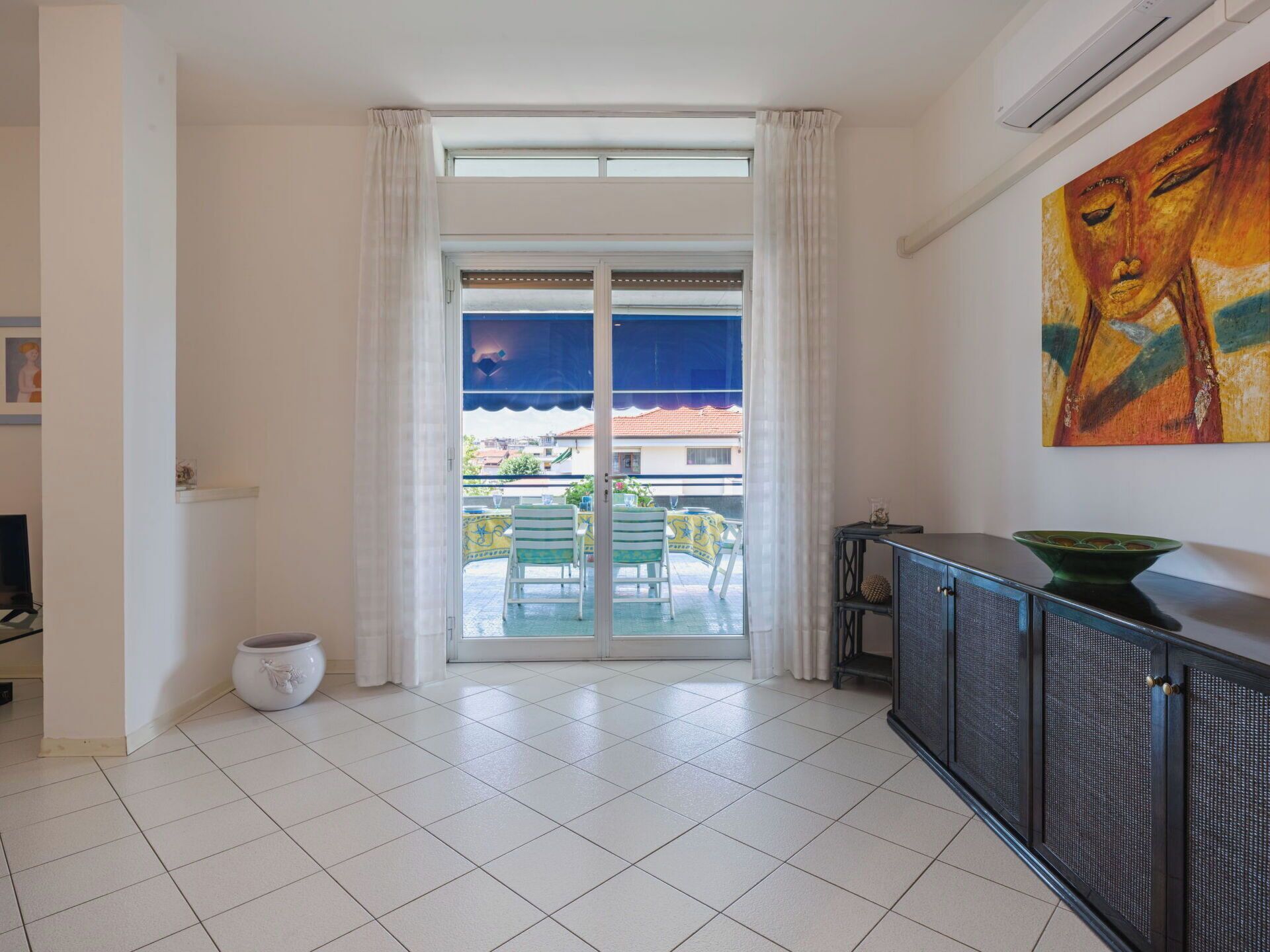 Habitació amb una gran porta corredissa de vidre que dona a una zona exterior amb cadires i taula.