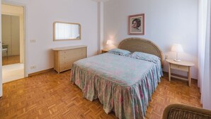 Ein Schlafzimmer mit Bett, Kommode, Nachttischlampen und einem Spiegel.